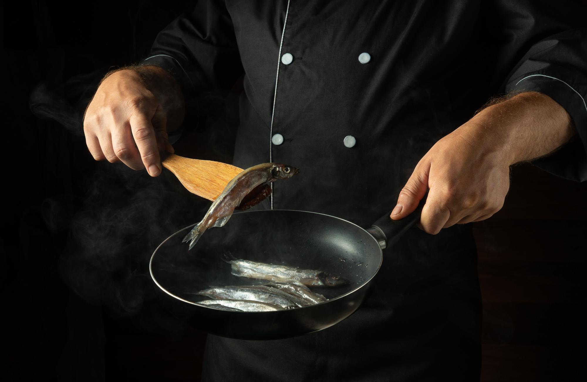 Hands searing fish on a pan